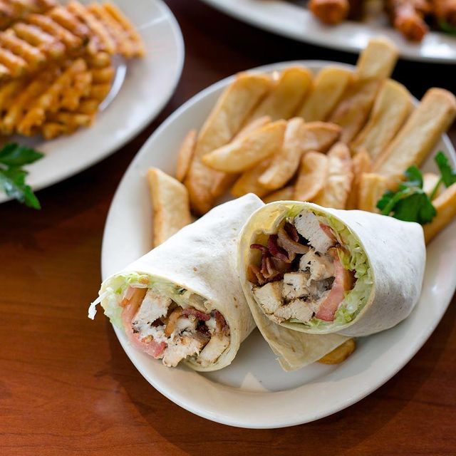 A plate of chicken wraps and fries on a table.